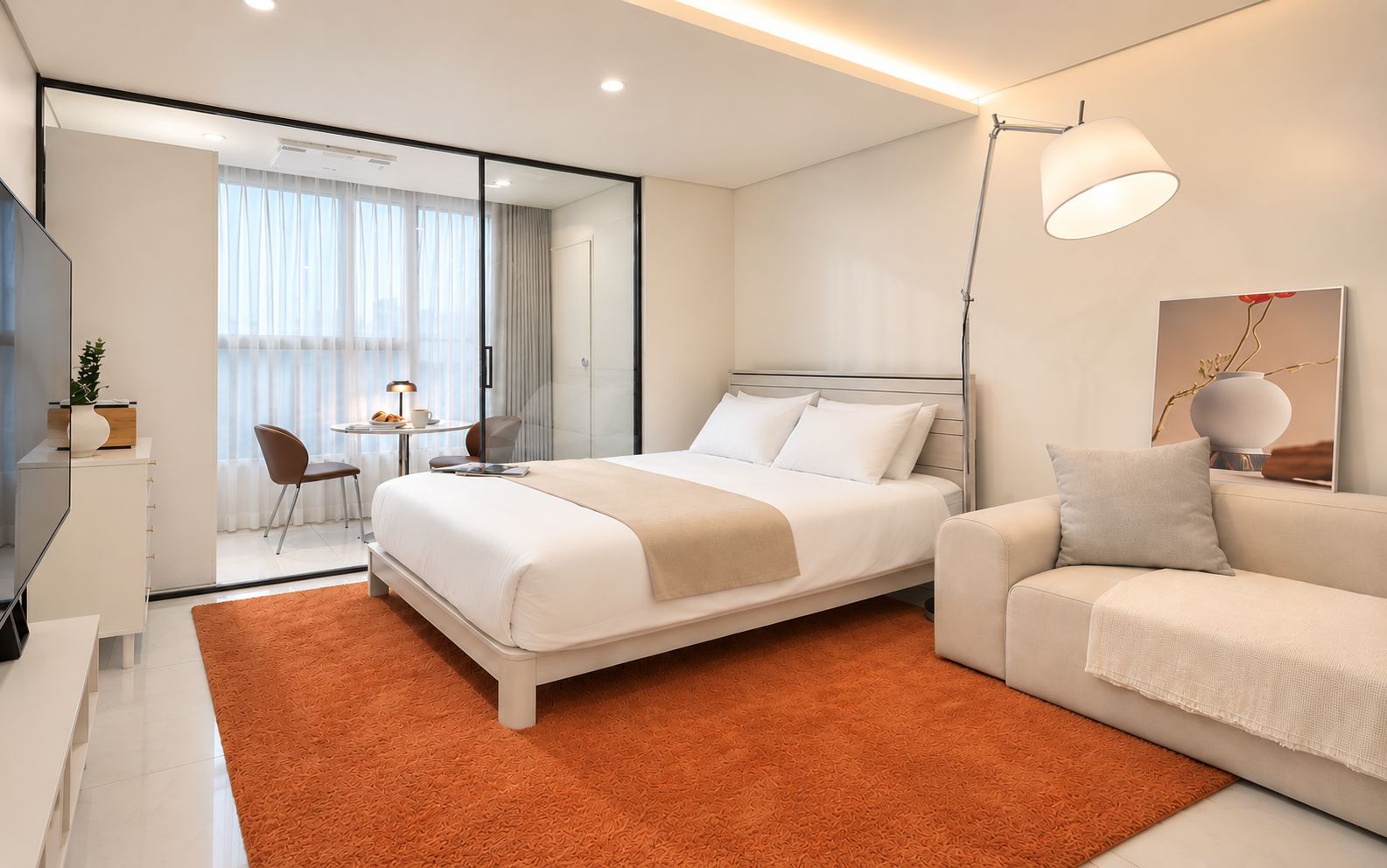 A modern hotel room with a bed, a sofa, a desk with a chair, and a large window with curtains.