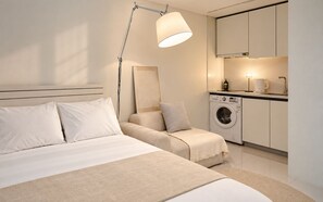 A modern bedroom with a bed, bedside lamp, and a kitchenette area with a washing machine. - UH FLAT THE SEOCHO (Seoul)