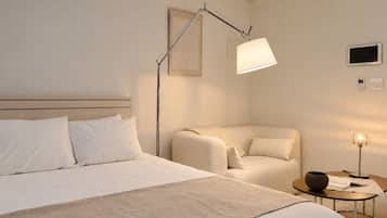 A hotel room with a bed, a chair, a bedside table with a lamp, and a wall-mounted TV.