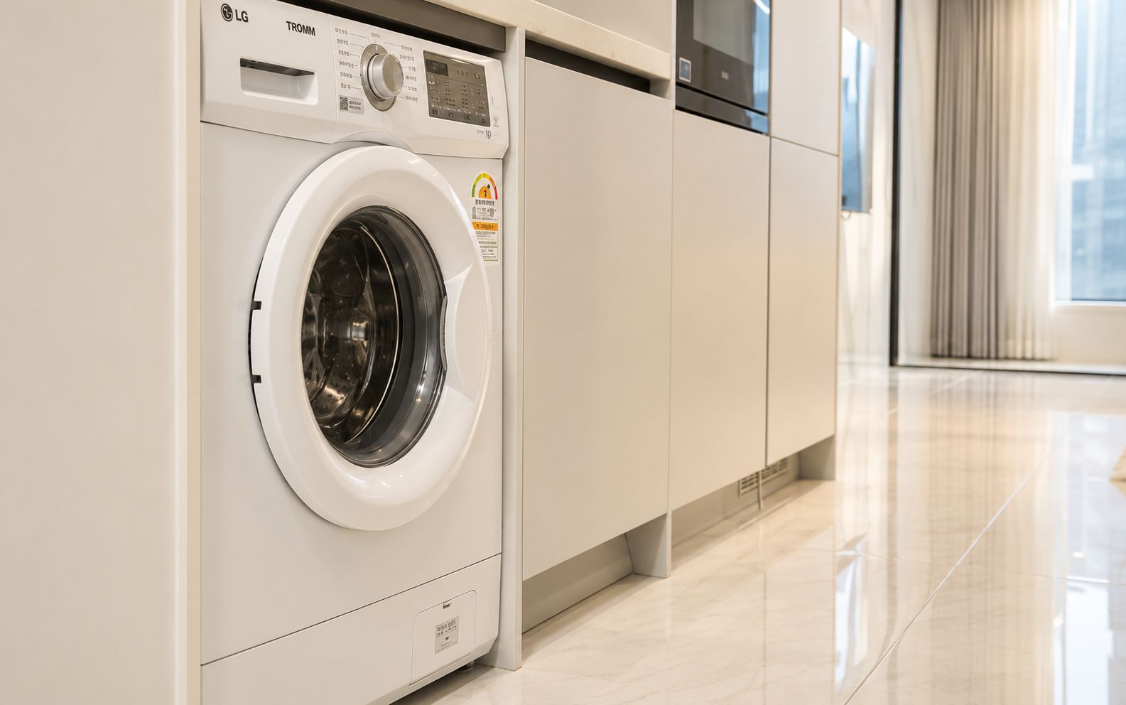 A modern laundry room with a front-loading washing machine, a dryer, and a cabinet.