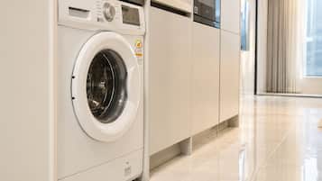 A modern laundry room with a front-loading washing machine, a dryer, and a cabinet.