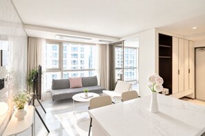 A modern living room with a sofa, a coffee table, and a dining area with a white marble table. - UH FLAT THE SEOCHO (Seoul)