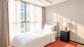 A hotel room with a large bed, a nightstand, a lamp, and a view of buildings through the window.