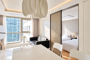 A modern hotel room with a large bed, a sofa, a dining table, and a view of a cityscape through floor-to-ceiling windows. - UH FLAT THE SEOCHO (Seoul)