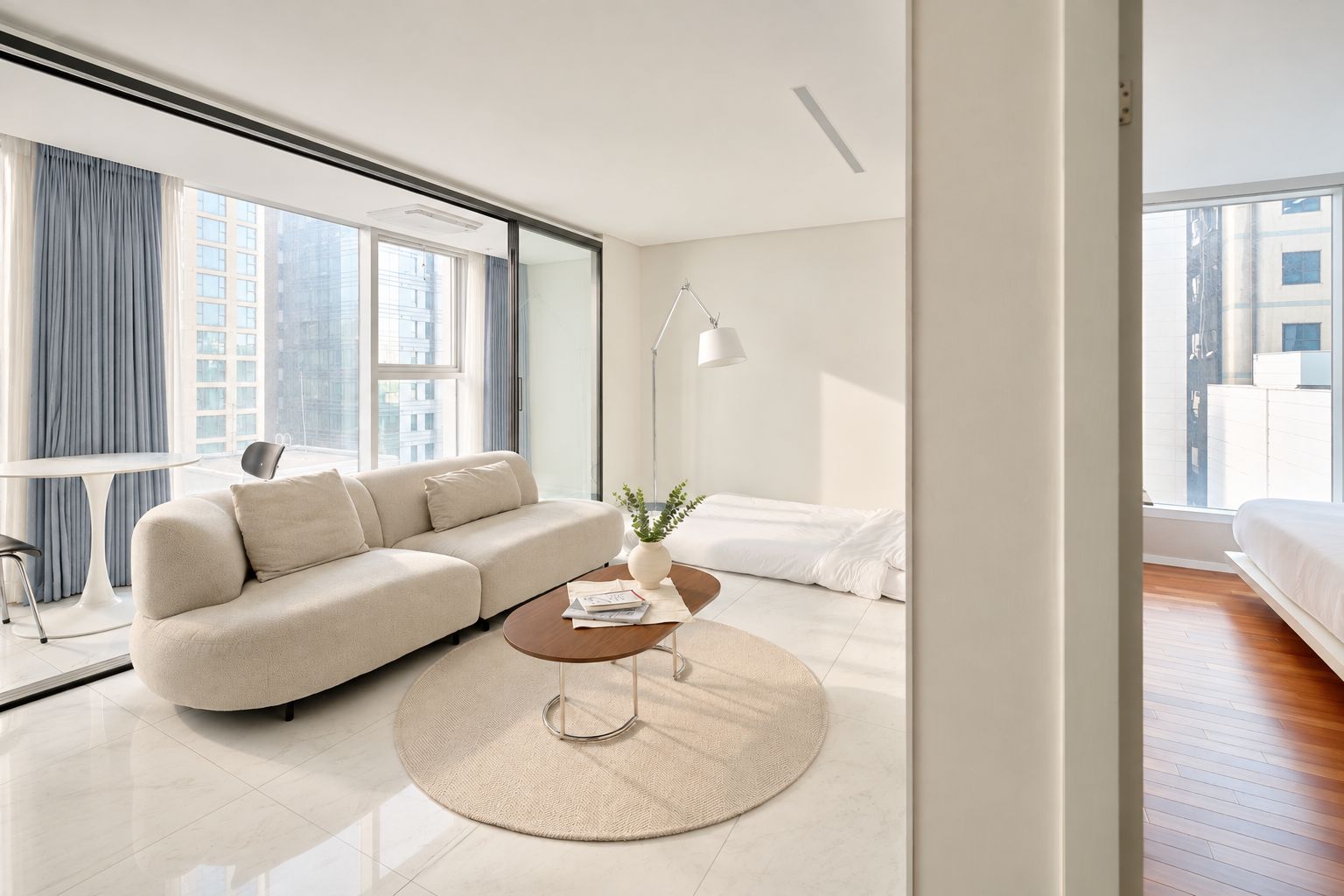 A modern living room with a sofa, coffee table, and a view of the city through large windows.