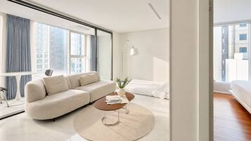 A modern living room with a sofa, coffee table, and a view of the city through large windows.