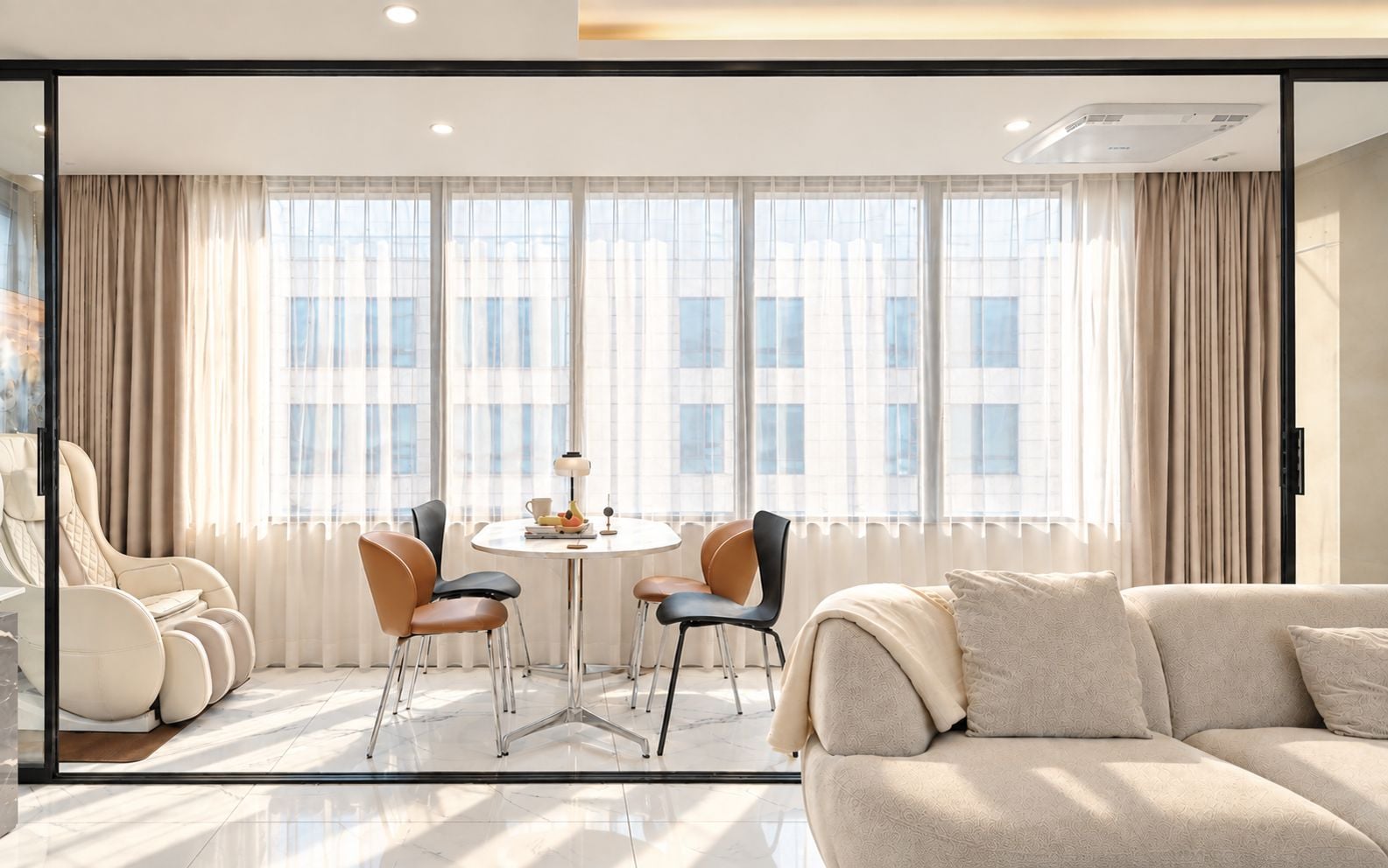 Un salon moderne avec un canapé, deux fauteuils, une table ronde et une grande fenêtre avec des rideaux.
