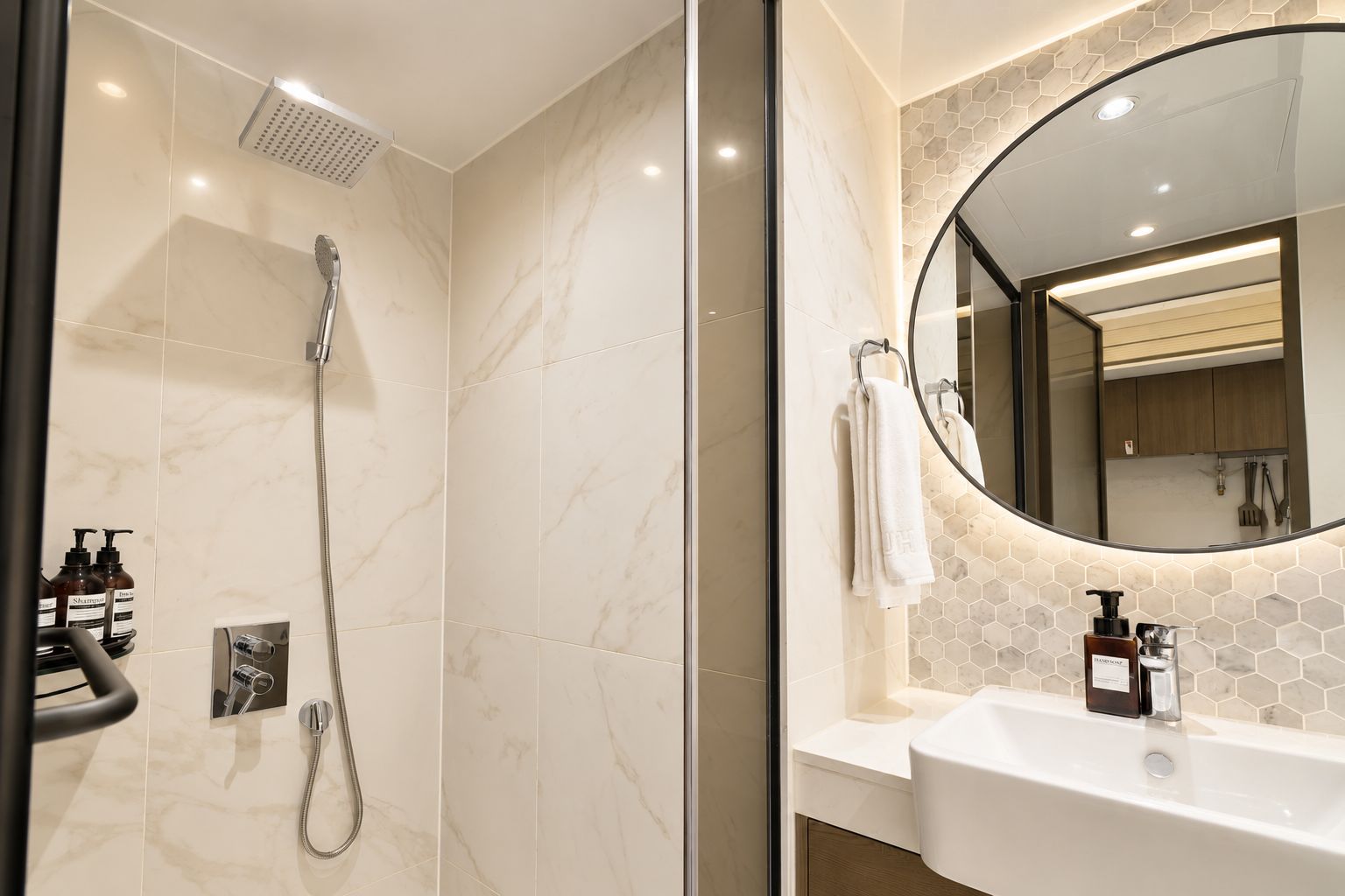 A modern bathroom with a shower, a sink, and a mirror.