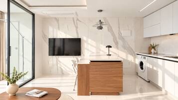 A modern kitchen with a built-in washing machine, a flat-screen TV, and a wooden island.