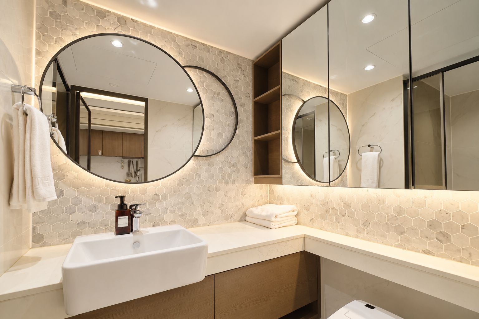 Un baño moderno con un lavamanos blanco, dos espejos grandes y un respuesto de azulejos hexagonales.