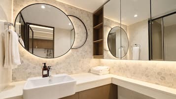 Un baño moderno con un lavamanos blanco, dos espejos grandes y un respuesto de azulejos hexagonales.