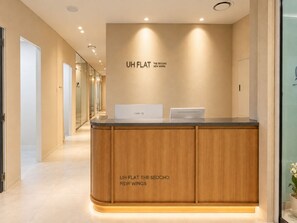 A reception desk with a wooden finish and a sign above it. - UH FLAT THE SEOCHO (Seoul)