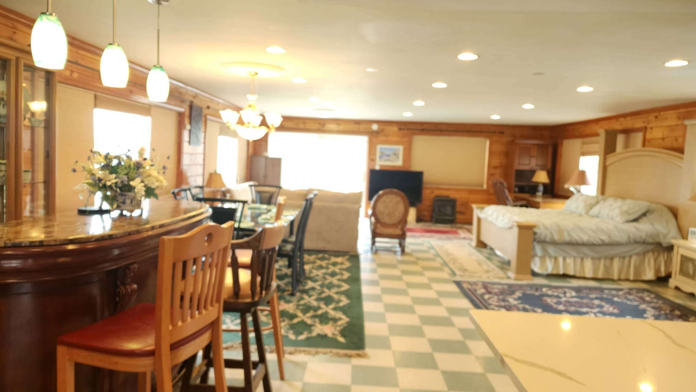 A room with a bar, dining area, and a bed.