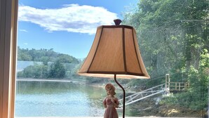 A statue of a woman in a dress on a table by a window overlooking a lake and a bridge. - Large beautiful ocean front studio with private dock (Harpswell)