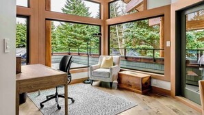 A modern room with large windows, a desk, a chair, and a small table. - Mountain view chalet w/ hot tub (Whistler)