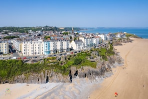 A coastal town with a prominent beach, terraced houses, and a church spire. - Penlan - Close to Town and Beaches (Tenby)