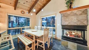 Un interior de madera con chimenea, ventanas amplias y un comedor.