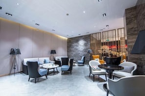 A modern lounge area with sofas, armchairs, and tables, featuring a stone accent wall and recessed lighting. - Shangcheng Pusu Hotel (Wenzhou)