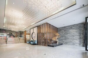 A modern lobby with a staircase, a reception desk, and a decorative wall. - Shangcheng Pusu Hotel (Wenzhou)