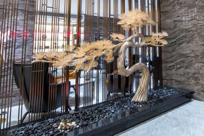 A decorative indoor plant arrangement with a unique design, placed on a black surface with a textured wall in the background. - Shangcheng Pusu Hotel (Wenzhou)