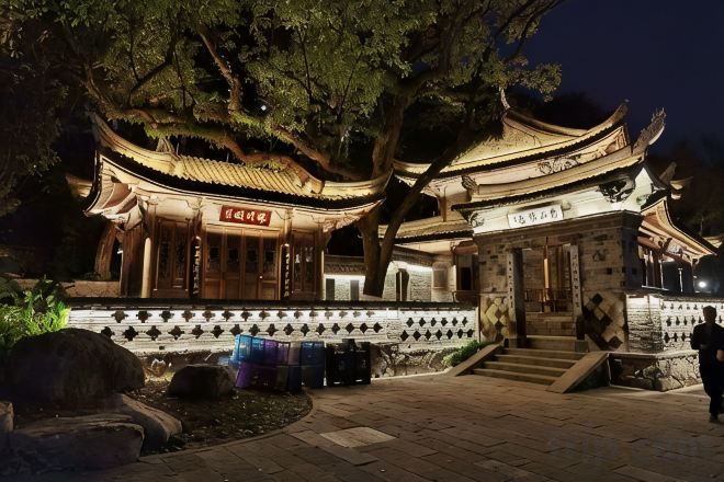 A traditional Chinese pavilion with a tiled roof, surrounded by stone steps and a stone railing.