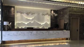 A reception desk with a marble top and a modern light fixture above it.