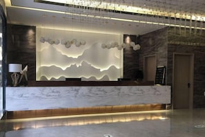 A reception desk with a marble top and a modern light fixture above it. - Shangcheng Pusu Hotel (Wenzhou)