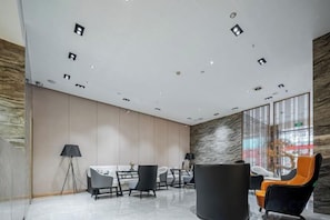 A modern interior with a high ceiling, recessed lighting, a marble floor, and a seating area with chairs and a table. - Shangcheng Pusu Hotel (Wenzhou)