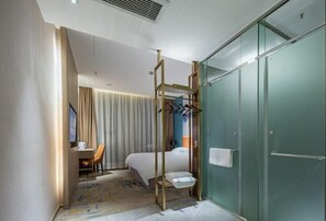 A hotel room with a bed, a desk, and a glass-enclosed shower area. - Shangcheng Pusu Hotel (Wenzhou)