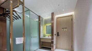 A modern bathroom with a glass shower enclosure, a wooden vanity, and a towel rack.
