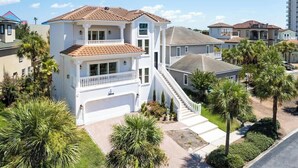 A two-story house with a white exterior, a balcony on the upper floor, and a front staircase leading to the garage. - Coastal Villas (Destin)