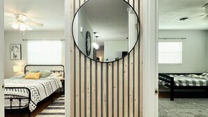 Une chambre à coucher avec un lit, un miroir rond et une cloison en lattes de bois.
