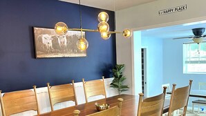 Un coin repas avec une table et des chaises en bois, un lustre et un tableau accroché au mur.