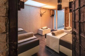 Ein Spa-Raum mit zwei Betten, einem Kamin und einer Steinwand.