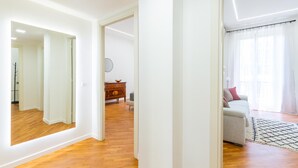 Eine moderne Wohnung mit Holzböden, einem Holzkoffer, einem runden Spiegel und einem Sofa mit gemustertem Teppich.