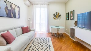Ein modernes Wohnzimmer mit einer Couch, einem Esstisch und einem Fernseher.