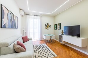 A modern living room with a sofa, a TV, a dining table with chairs, and artwork on the walls. - Stanzione Classy Flat at Vomero Central (Naples)
