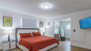 A bedroom with a bed, nightstands, a TV, and artwork on the walls. - Modern 4 Bed 2 Bath home with a pool, King bed sleeps 10 in Orlando close to UCF (Orlando)