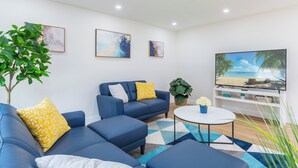 A modern living room with a blue sofa set, a coffee table, and a flat-screen TV. - Modern 4 Bed 2 Bath home with a pool, King bed sleeps 10 in Orlando close to UCF (Orlando)