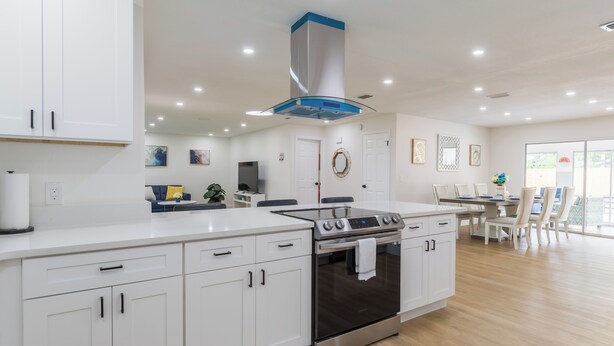 A modern kitchen with white cabinets, a stainless steel stove, and a large island. - Modern 4 Bed 2 Bath home with a pool, King bed sleeps 10 in Orlando close to UCF (Orlando)