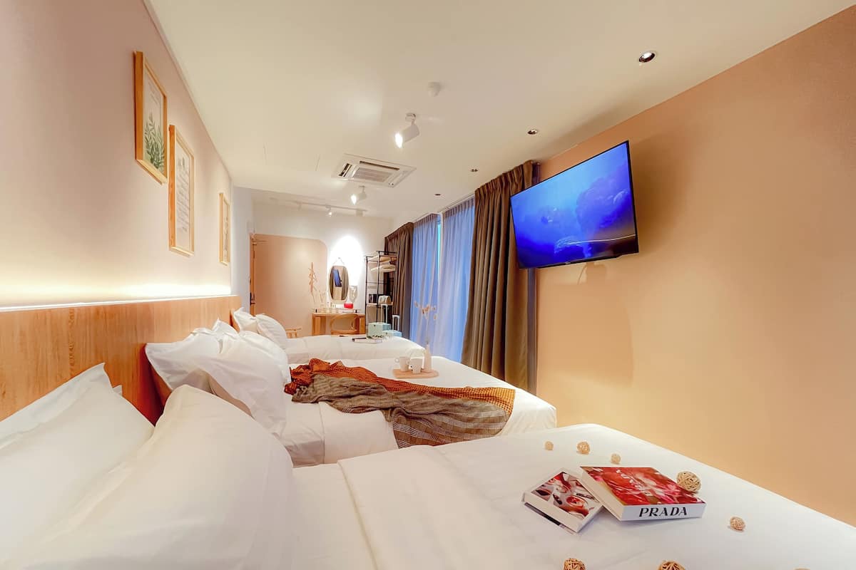 A hotel room with two beds, a TV, a desk, and a mirror.