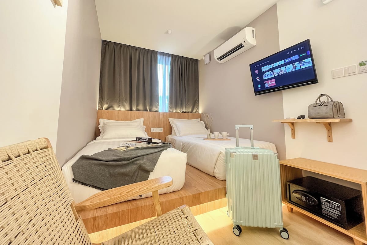A hotel room with a bed, a desk, a TV, and a radiator.