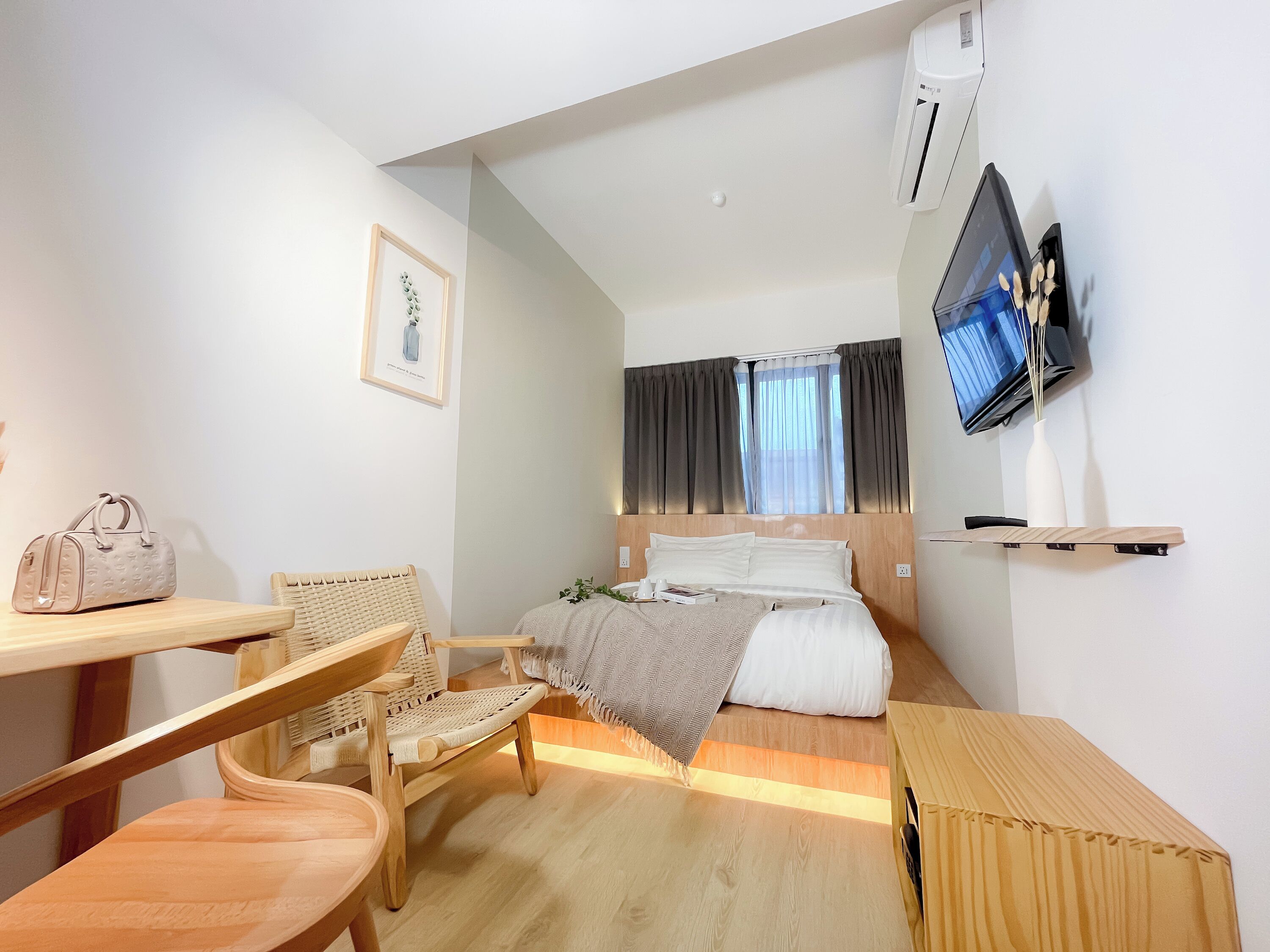 Habitación de hotel con cama, escritorio, silla, televisión y ventana con cortinas.
