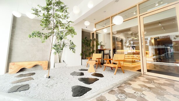 A modern interior with a seating area, a reception desk, and a large window. - Sleep Box Penang (George Town)