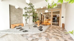 A modern interior with a central seating area, a small tree, and a patterned floor. - Sleep Box Penang (George Town)