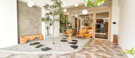 A modern interior with a central seating area, a small tree, and a patterned floor.