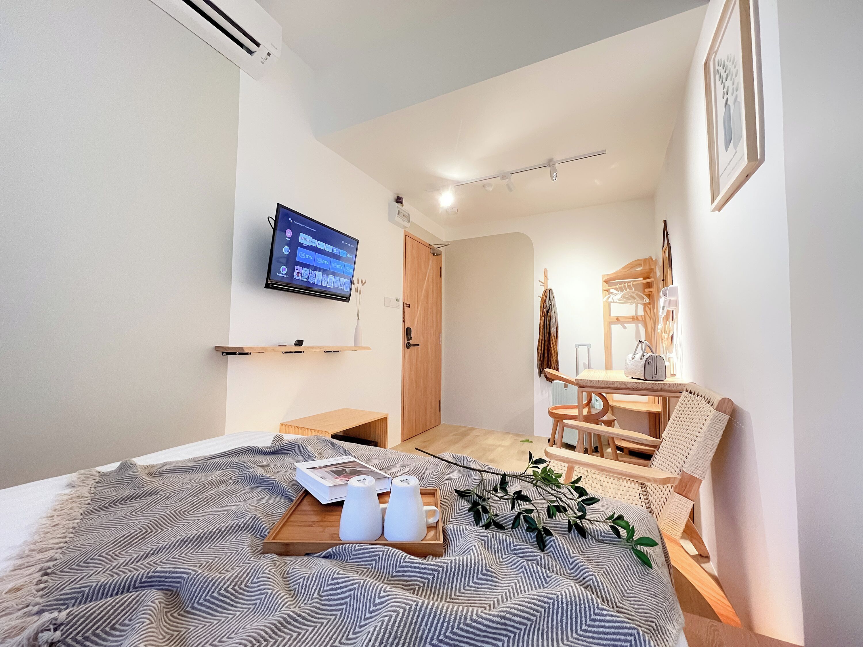 Ein modernes Schlafzimmer mit einem Bett, einem Wand-Fernseher, einem Holznachttisch und einem Sessel.