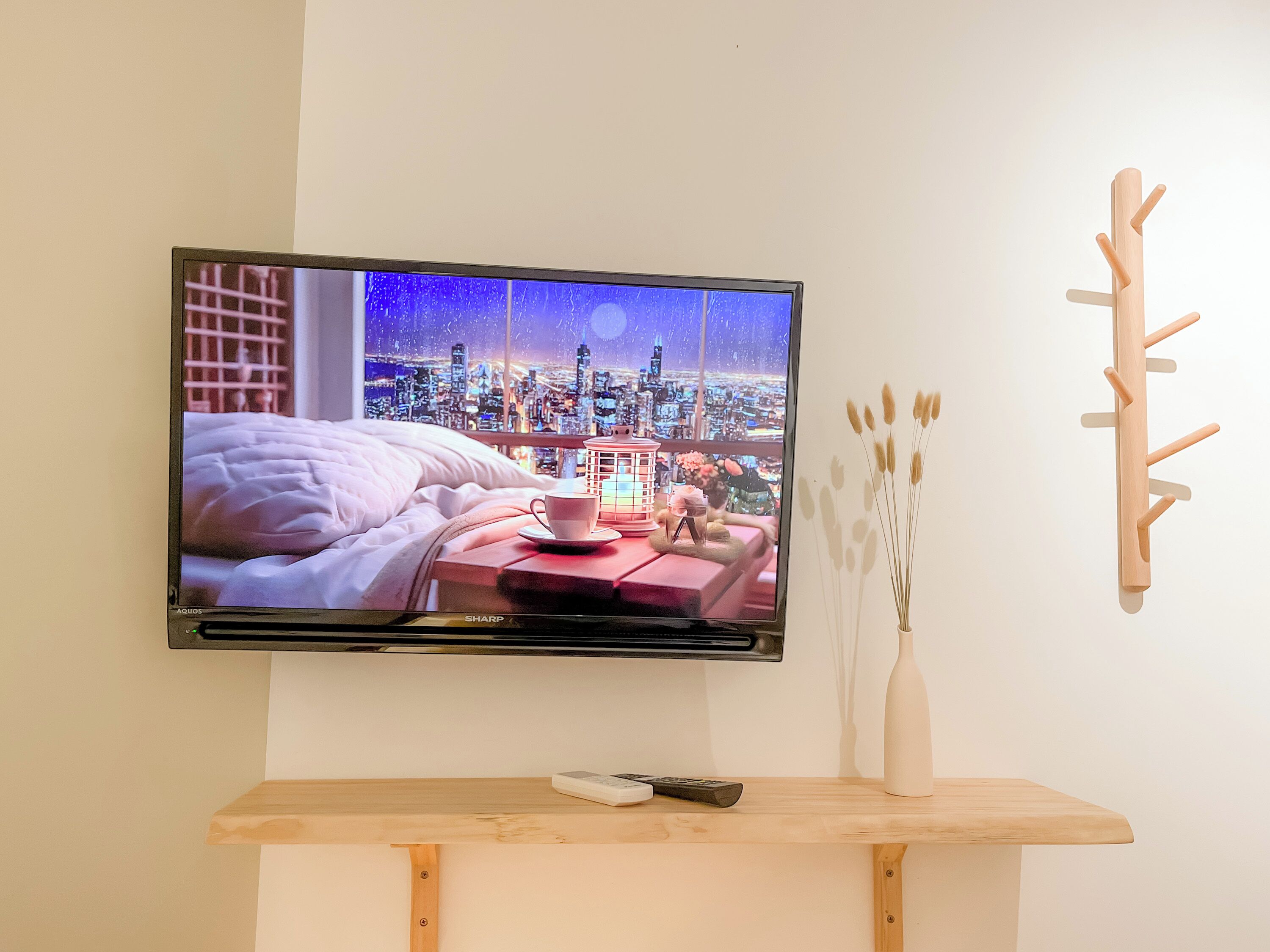 Ein an der Wand befestigter Fernseher zeigt eine nächtliche Stadtansicht.
