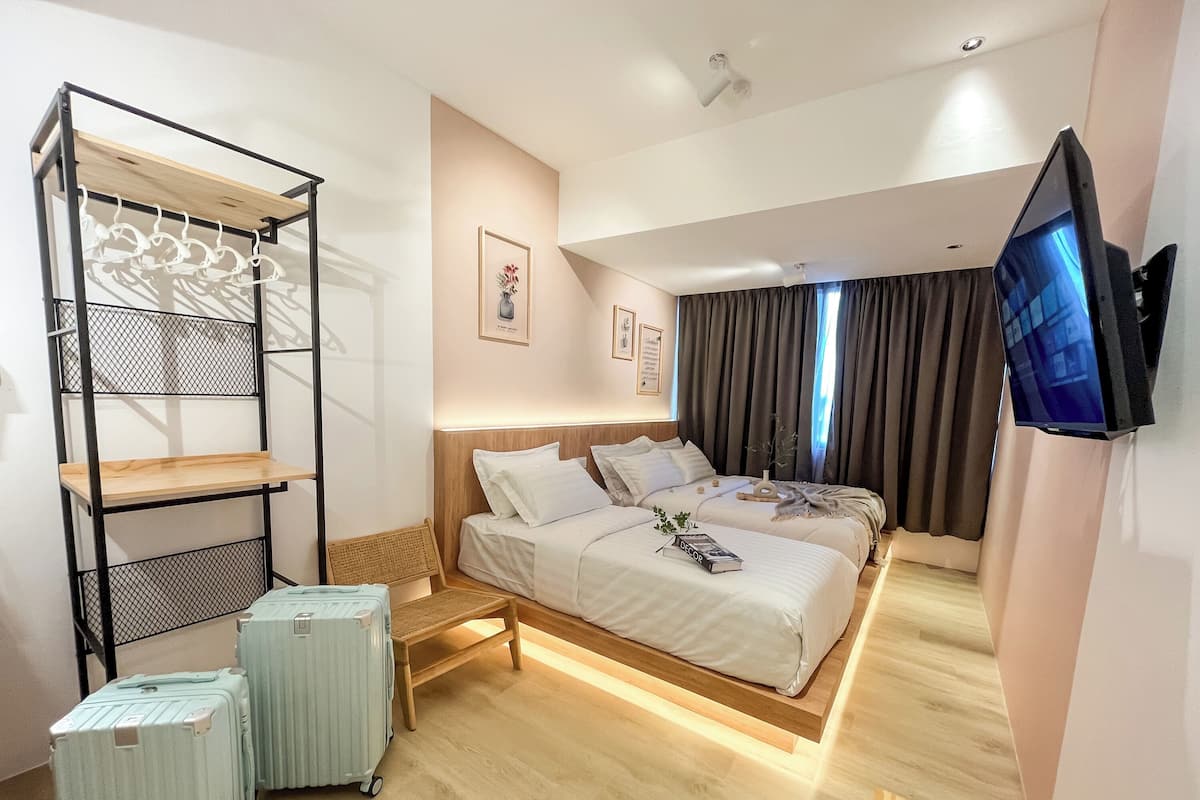 A hotel room with a bed, a TV, a shelf with clothes, and luggage.