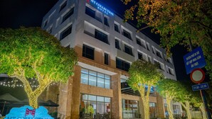 A modern hotel building with illuminated signage, outdoor seating, and a clear night sky. - MT Collection Hotel (Hoa Lu)